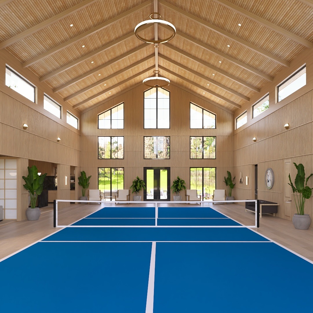 Bright indoor tennis court with blue flooring, surrounded by large windows and modern decor, creating a spacious and inviting atmosphere.