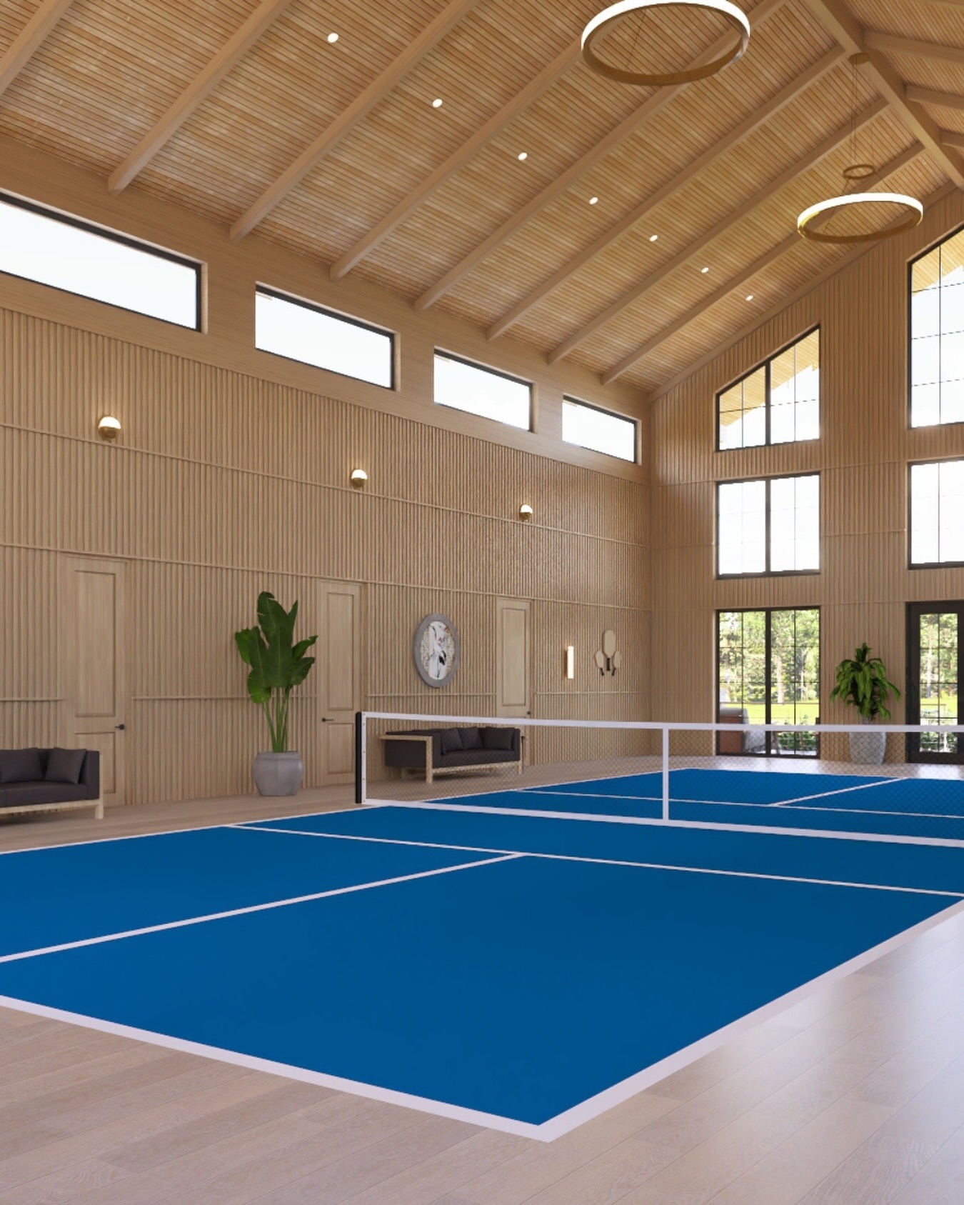 Indoor tennis court featuring a blue surface and natural wood accents. Large windows allow sunlight, enhancing the modern, open design.